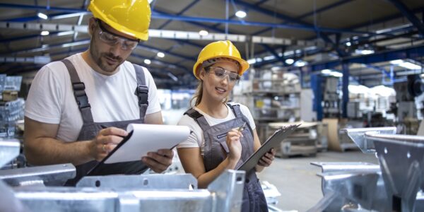 Factory workers checking quality of products in large industrial hall.